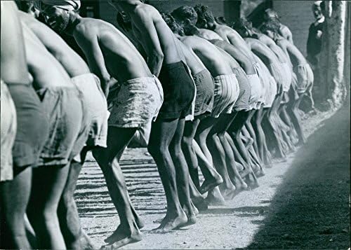Гроздобер фотографија на половина голи мажи кои стојат по ред.