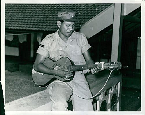 Гроздобер фотографија на еден од полковникот Симболен39; тело чувар на телохранител како свири гитара.